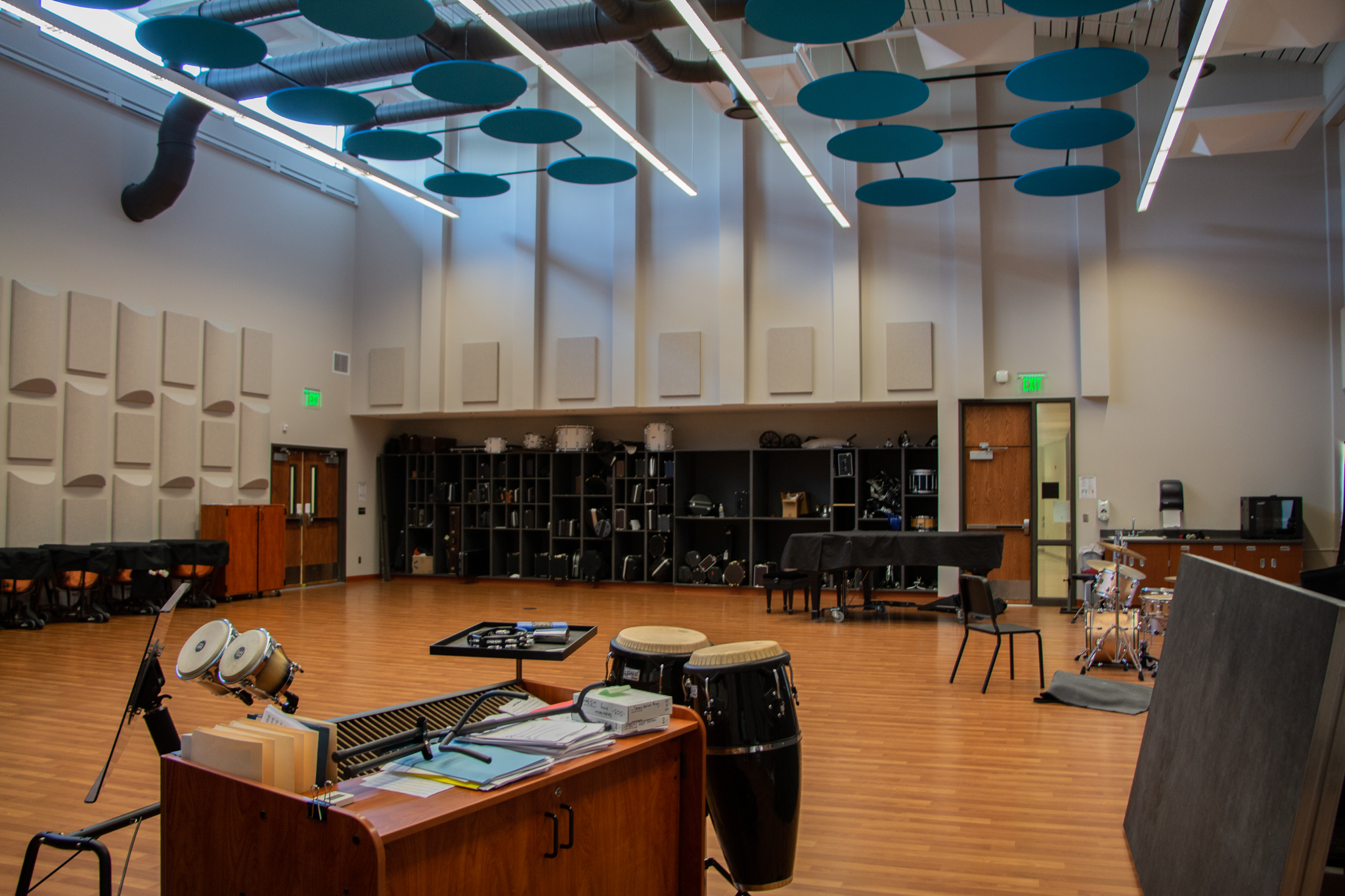 Jindra Band Room with acoustic wall and ceiling tiles, baby grand piano, sink, chairs and music stands.