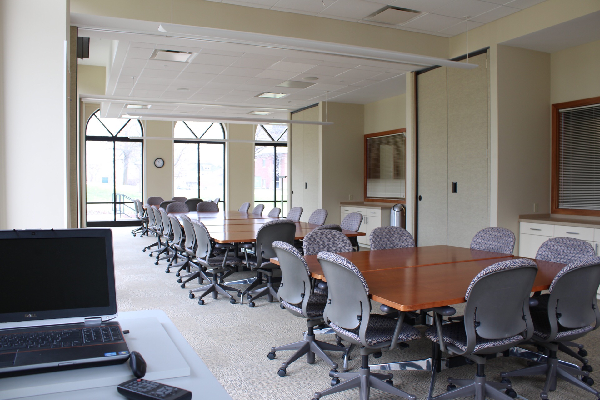 View from South to North end of CATS Conference room showing tables, chairs, storage cabinets and laptop on a movable podium.