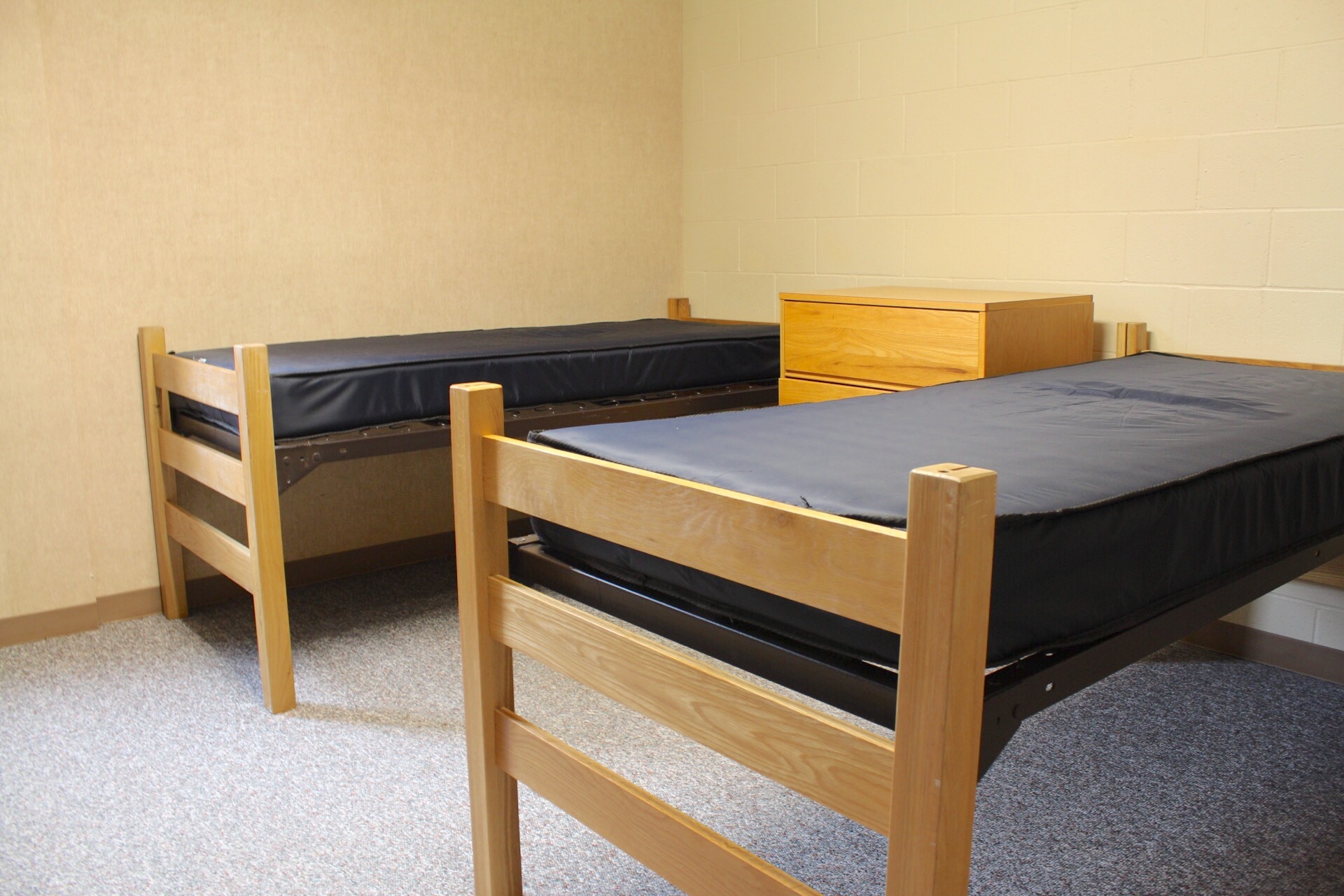 Centennial Complex room with 2 bed frames, mattresses and a dresser placed between them.