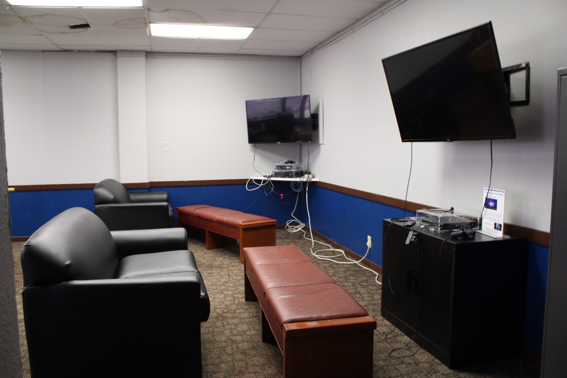 Game Room showing an additional wall mounted tv, consoles and couches for video games.