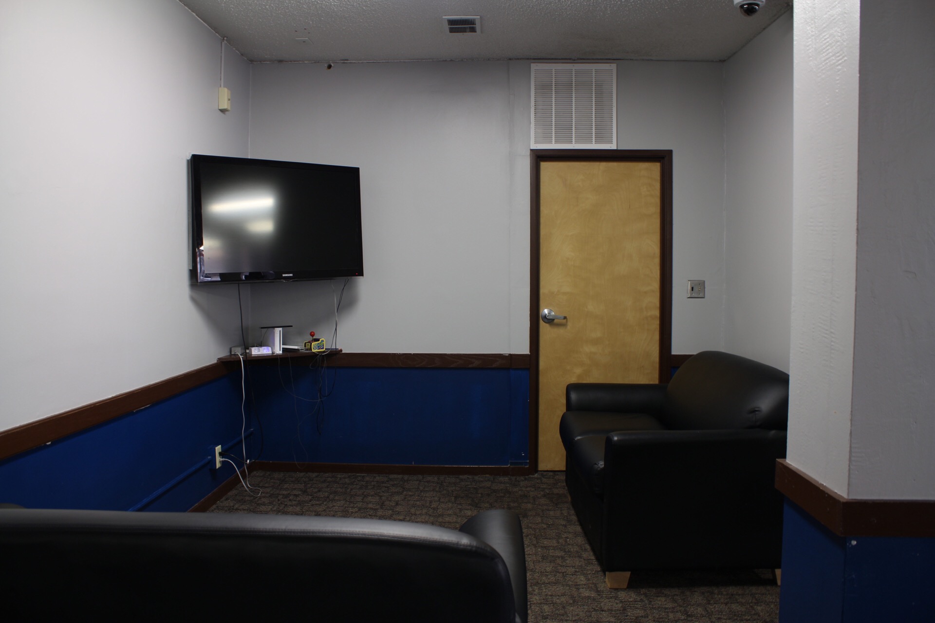 Game Room showing a corner mounted tv, consoles and couches for video games.
