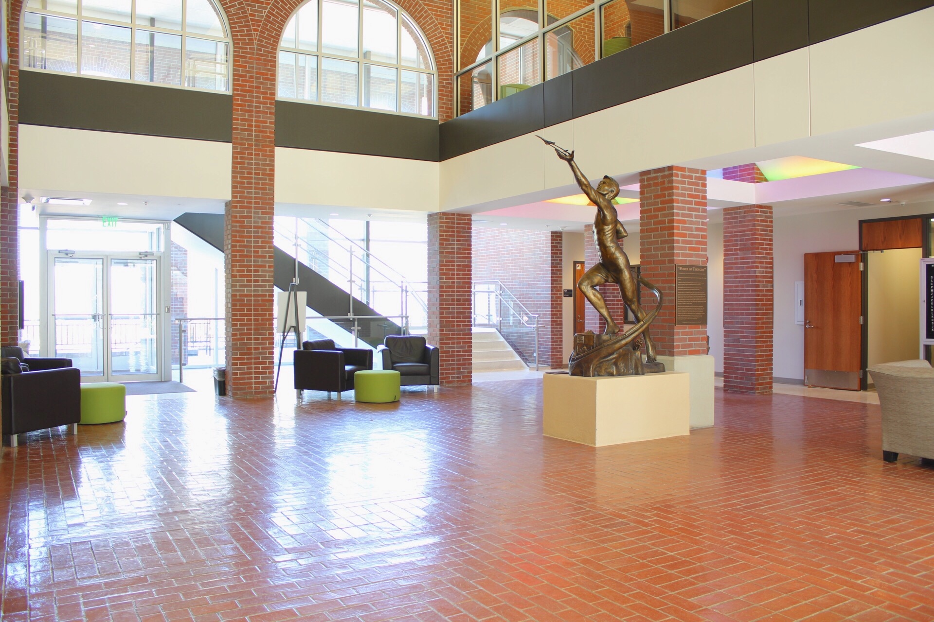 Jindra lobby showing brick floor, brick pillars, The Power of Thought Statue, seating areas and stairs to second floor.