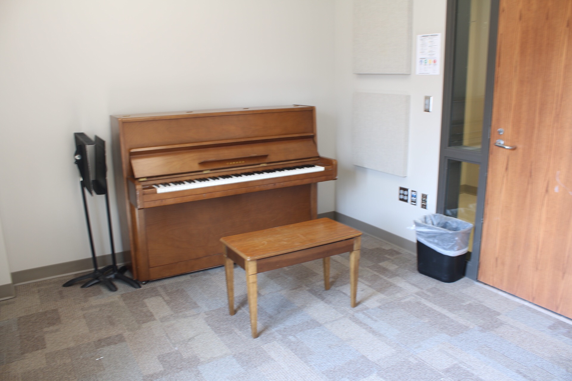 Jindra Fine Arts Practice Room with a piano, bench and a music stand.