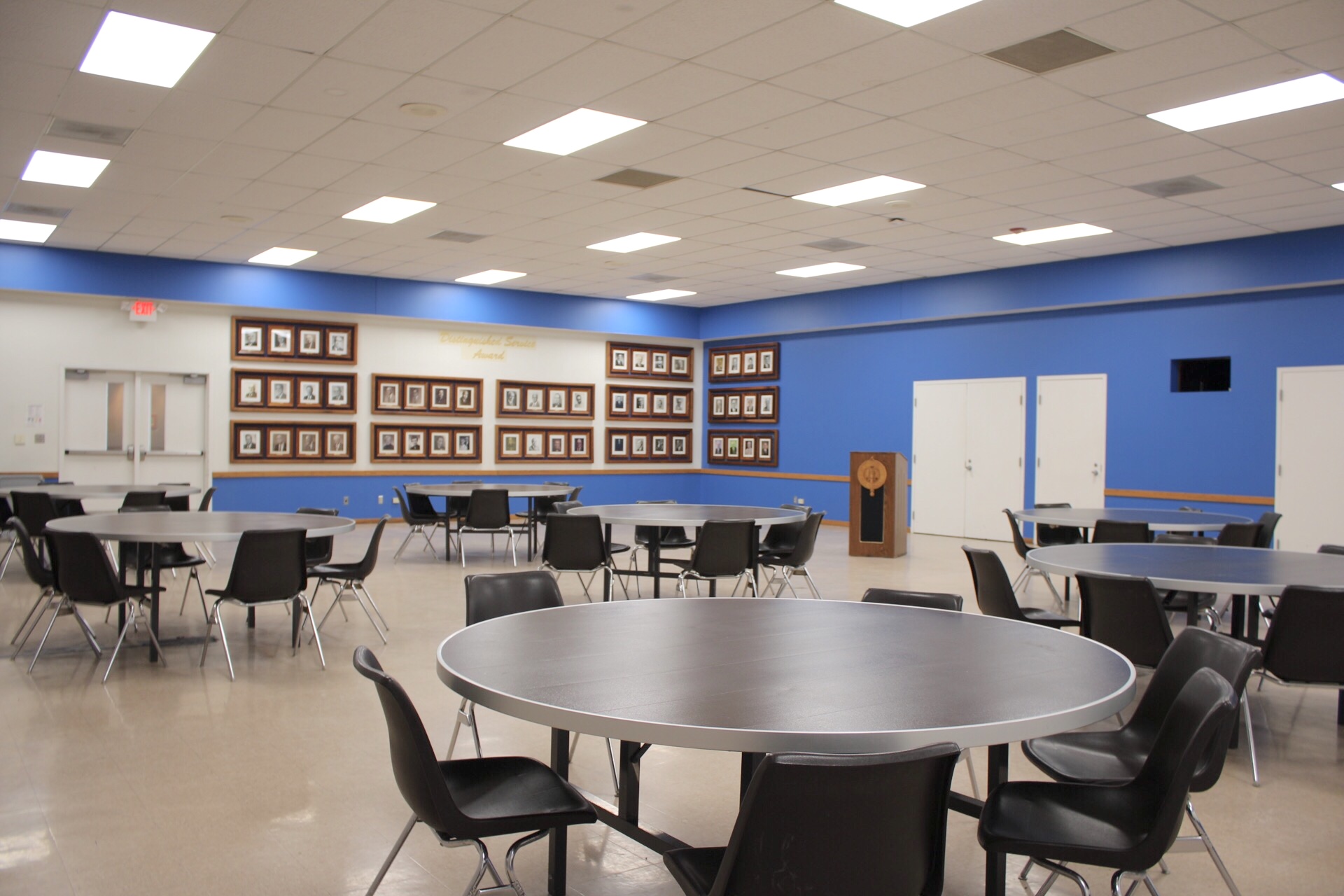 Live Oak Room showing tables, chairs, movable podium and photos of distinguished faculty member on 2 walls.