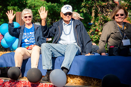 Alums riding on a float during the Homecoming Parade.