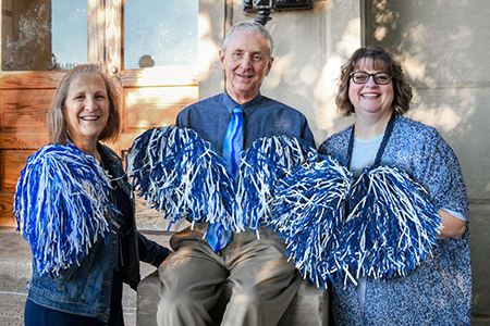 Foundation staff holding pom poms in front of TJ Majors.