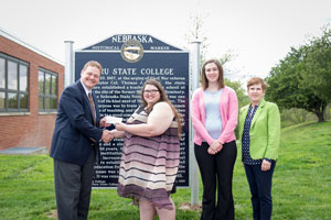 Todd Simpson, Chief Executive Officer of the Peru State College Foundation, receives a check from Michelle Kaiser, Phi Alpha Theta President in front of Peru State College’s new historical marker with Samantha Jackson, PAT Secretary Treasurer and Dr. Sara Crook, co-advisor to Phi Alpha Theta.