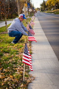Tyson Buettgenback helps line Park Avenue with flags as part of the Veterans Day recognition at Peru State College.