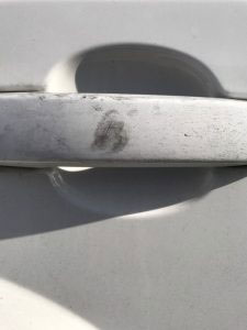Close up of finger print on white car door handle.