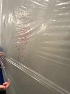 Close up of blood spatter on plastic hanging drop cloth.