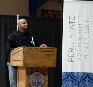 Aaron Davis next to the Distinguished Speaker Series Banner.