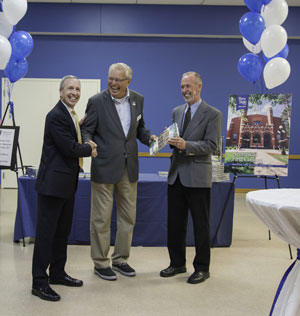 Larry Green (center), chairman of the Peru State Foundation Board of Directors, accepts the ceremonial delivery of the first book from author Dan Sullivan (right) and President Dan Hanson.