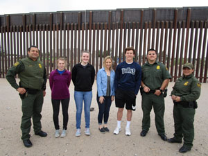 A portion of the border wall is behind the group.