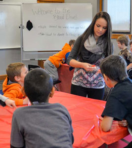 Students leaning across a table to get a better look at a student presenter.