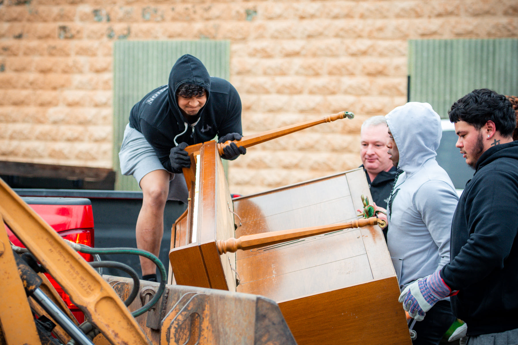 Students and Coach Ockinga load a piano on Peru Clean Up day.