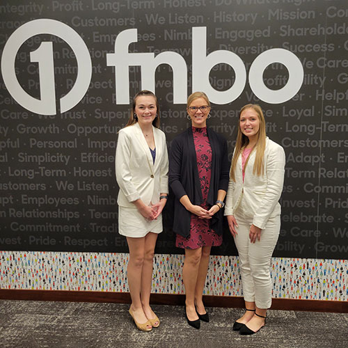 Azlyn Fendrick, Dr. Sheri Grotrian and Kaytlin Danner pose before a backdrop wall with FNBO bank logo.