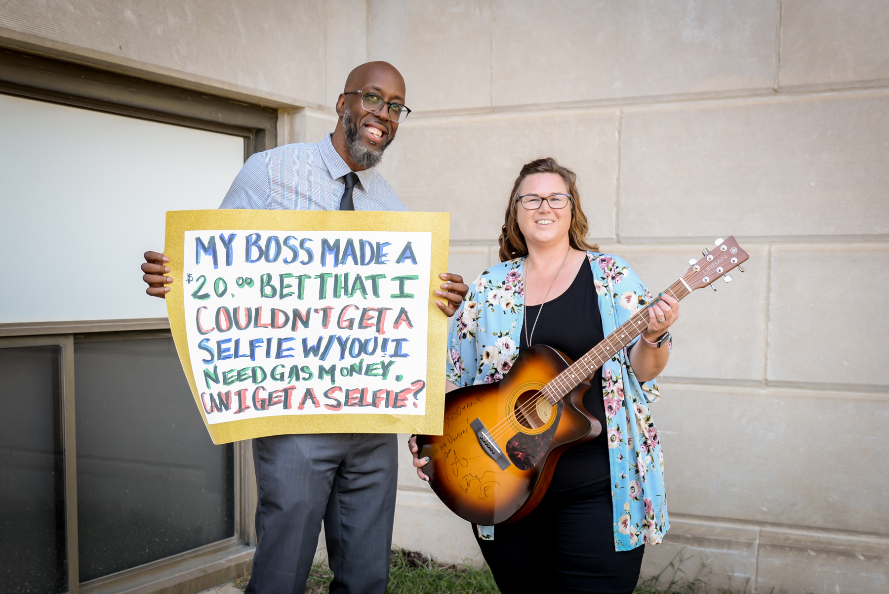 Dwayne Chism holding a sign, Stephanie Holmes holding a guitar